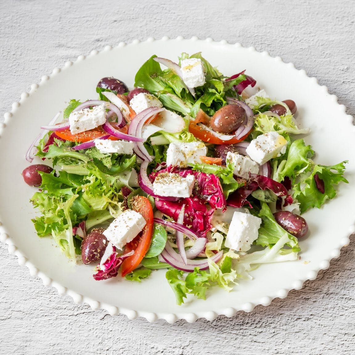 Mr Gyros Greek salad in Glasgow with feta cheese cubes, olives, onions, and fresh greens.