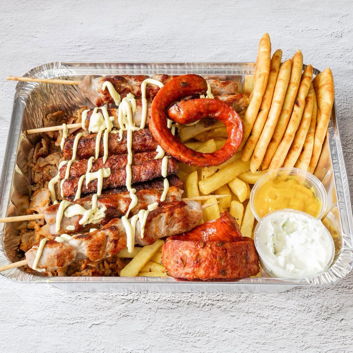 Mr Gyros in Glasgow meat platter box with souvlaki skewers, sausage, fries, and dips.